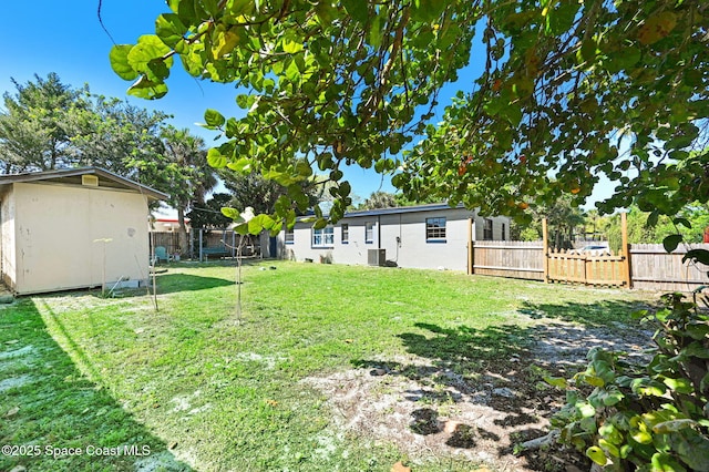 view of yard featuring a storage unit, central AC, a fenced backyard, and an outdoor structure