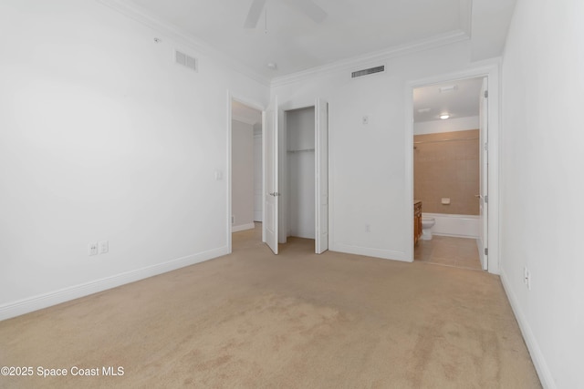 unfurnished bedroom featuring baseboards, visible vents, carpet floors, ensuite bath, and crown molding