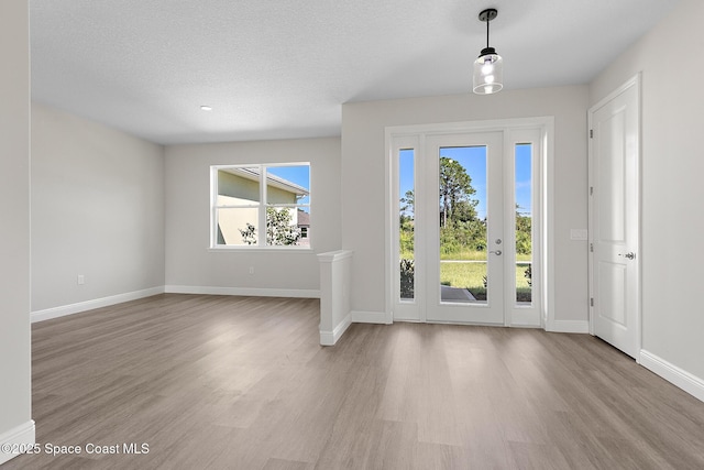 entrance foyer with a textured ceiling, baseboards, and wood finished floors