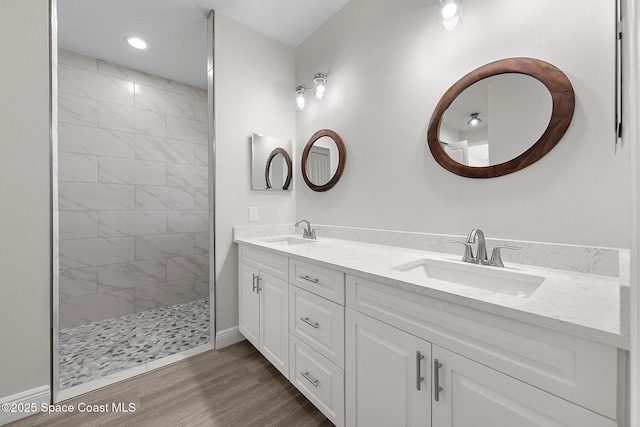 bathroom featuring a sink, walk in shower, wood finished floors, and double vanity