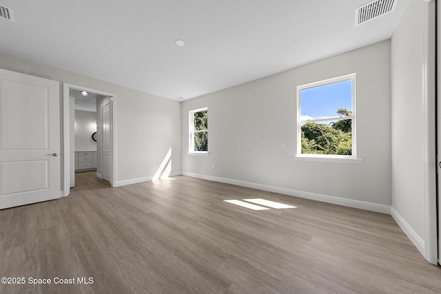 unfurnished room with light wood-style floors, visible vents, and baseboards