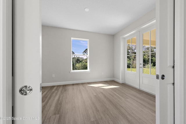 spare room featuring wood finished floors, baseboards, and french doors