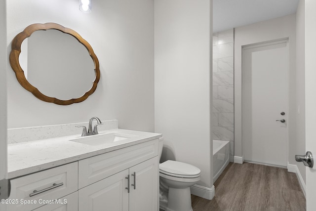 bathroom with vanity, toilet, wood finished floors, and baseboards