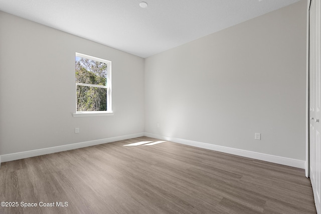 empty room with baseboards and wood finished floors