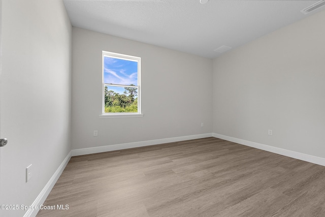 spare room with baseboards, visible vents, and light wood finished floors