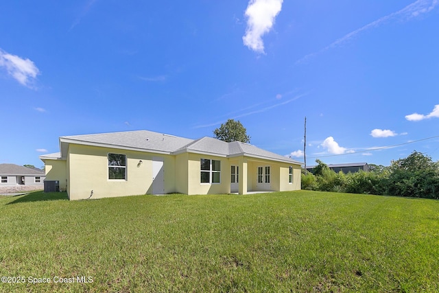 rear view of property featuring stucco siding, a lawn, and central AC unit