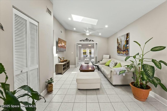 living room with visible vents, lofted ceiling with skylight, a ceiling fan, light tile patterned flooring, and baseboards