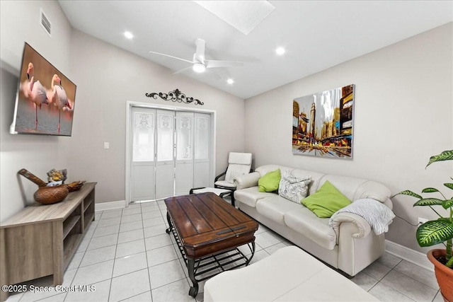 living area featuring light tile patterned floors, visible vents, lofted ceiling with skylight, and a ceiling fan