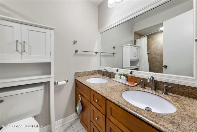 bathroom with a sink, toilet, double vanity, and tile patterned flooring