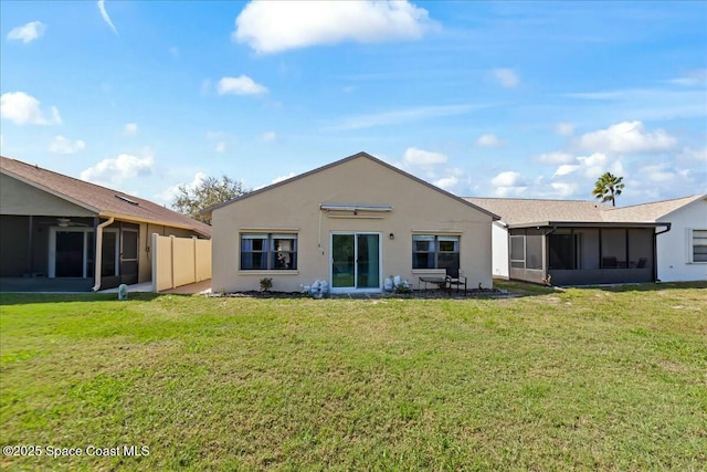 back of property with stucco siding, a lawn, fence, and a sunroom