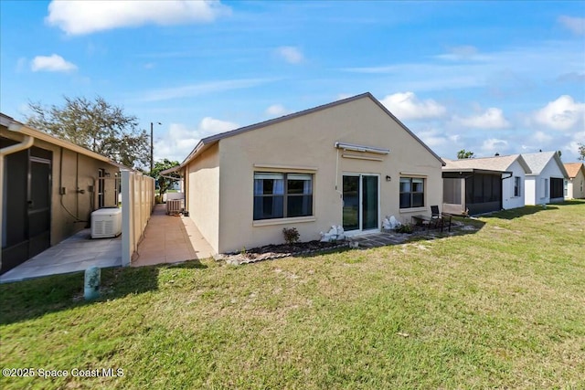 back of house with stucco siding, a lawn, and a patio area