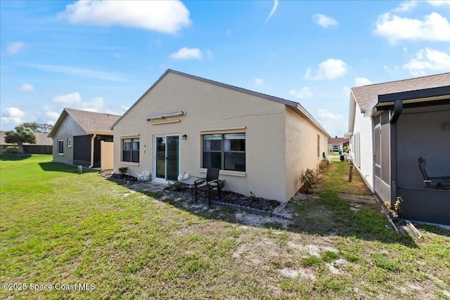 rear view of property featuring a lawn and stucco siding