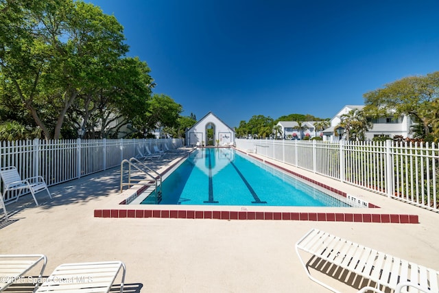 pool with an outbuilding, a storage unit, a patio, and fence