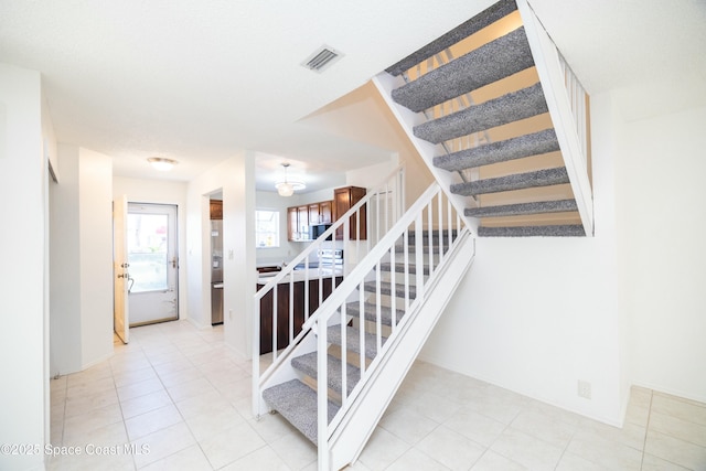 stairway with tile patterned floors and visible vents