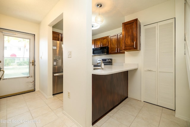 kitchen featuring light tile patterned floors, stainless steel appliances, baseboards, and light countertops