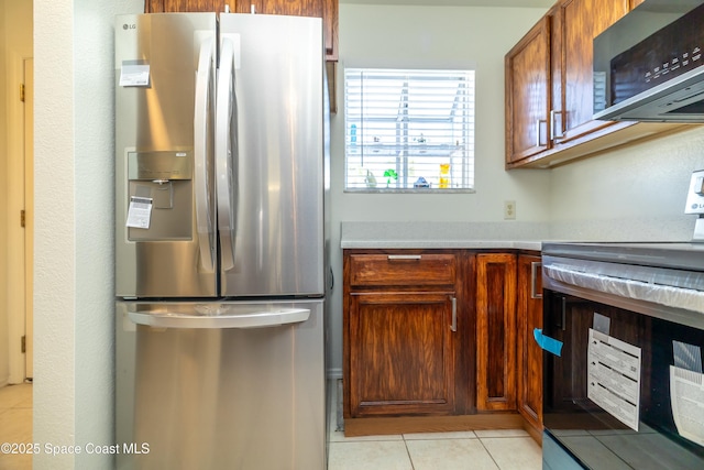 kitchen with stainless steel appliances, brown cabinets, light tile patterned flooring, and light countertops