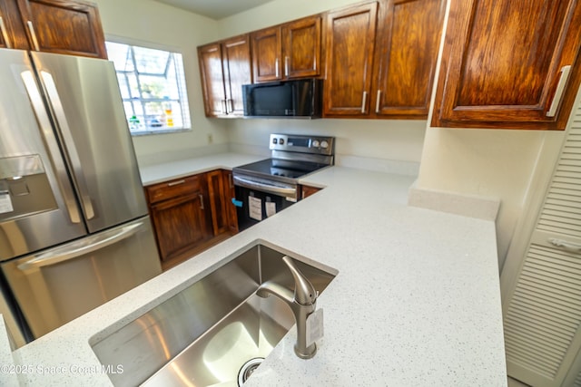 kitchen with appliances with stainless steel finishes, light stone countertops, and a sink