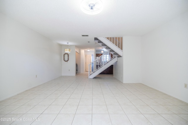 unfurnished living room with light tile patterned floors, visible vents, and stairs