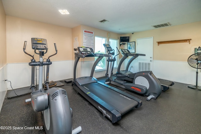 exercise room featuring visible vents and wainscoting