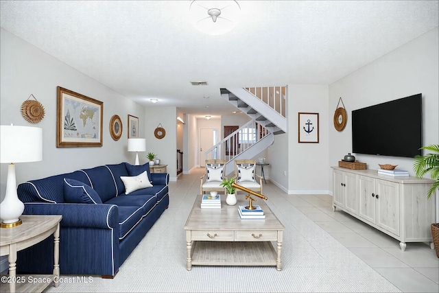 living room featuring light tile patterned floors, stairway, baseboards, and visible vents