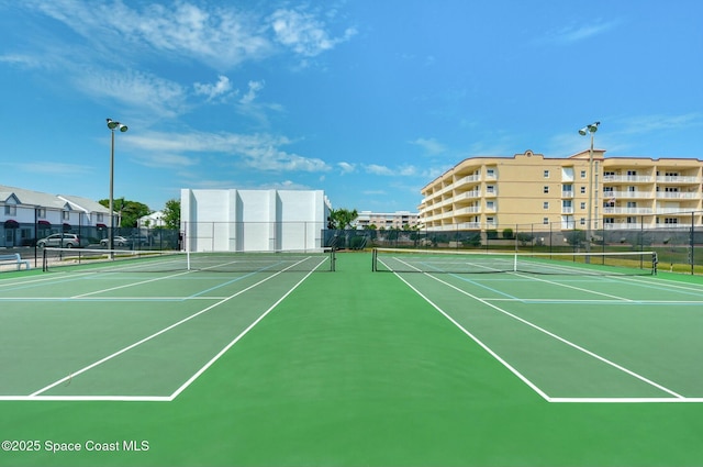 view of tennis court featuring community basketball court and fence