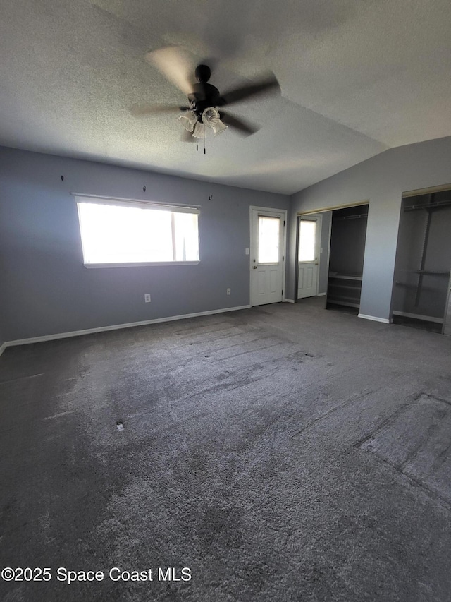 211 Cherie Down Ln, Cape Canaveral, FL 32920 - unfurnished bedroom featuring baseboards, two closets, lofted ceiling, carpet floors, and a textured ceiling