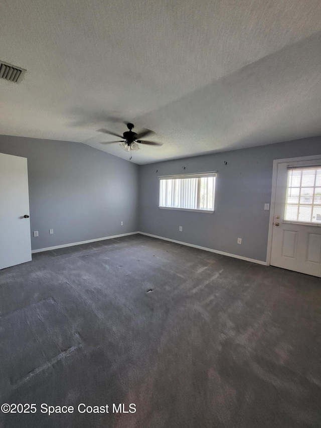 211 Cherie Down Ln, Cape Canaveral, FL 32920 - spare room featuring dark carpet, plenty of natural light, a ceiling fan, a textured ceiling, and baseboards