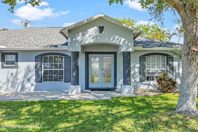 doorway to property with stucco siding, french doors, a shingled roof, and a yard