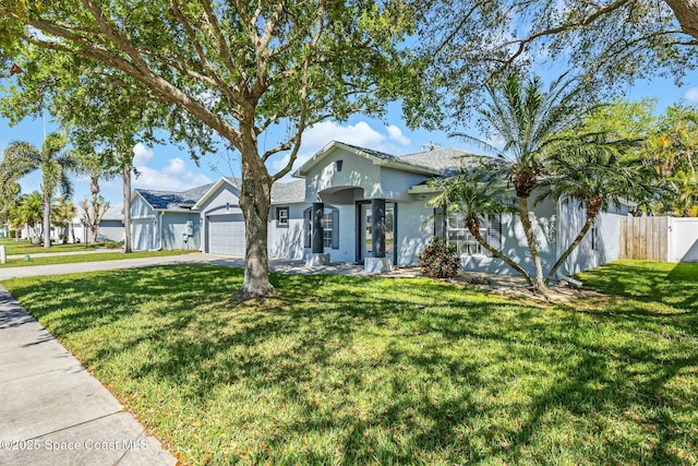 view of front of property with a front yard, fence, driveway, and stucco siding