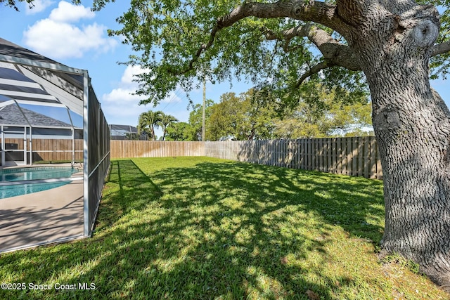 view of yard featuring a lanai, a fenced in pool, and a fenced backyard