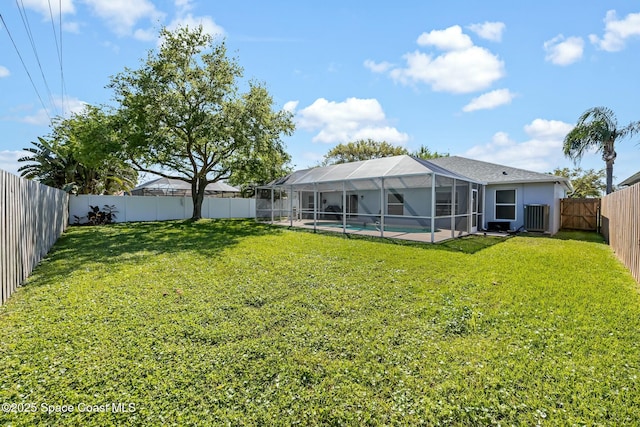 view of yard featuring glass enclosure, a fenced in pool, and a fenced backyard