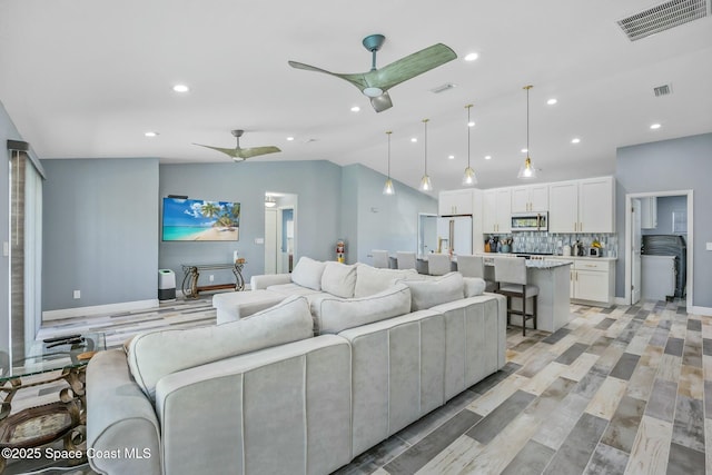 living area featuring vaulted ceiling, recessed lighting, visible vents, and ceiling fan