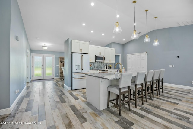 kitchen with tasteful backsplash, stainless steel microwave, visible vents, high end white fridge, and a large island with sink