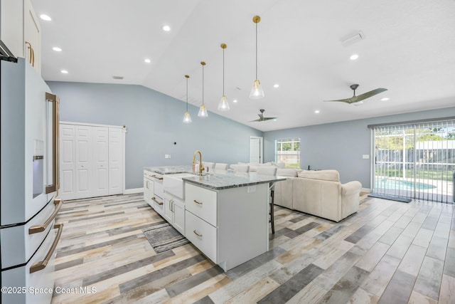 kitchen with a ceiling fan, a sink, vaulted ceiling, white cabinets, and white refrigerator with ice dispenser