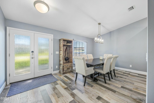 dining area featuring wood finished floors, visible vents, baseboards, an inviting chandelier, and french doors