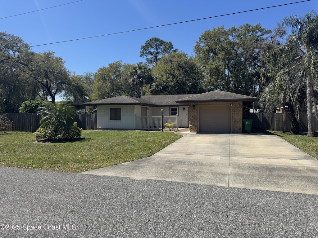 view of front of home with an attached garage, concrete driveway, a front yard, and fence