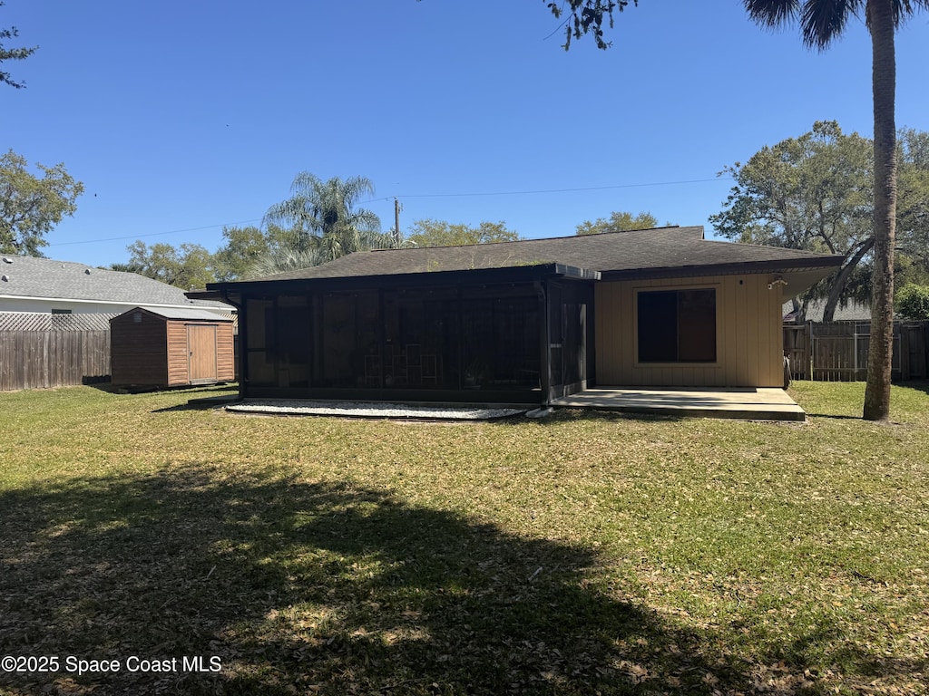 exterior space featuring a sunroom, a storage shed, a yard, and fence