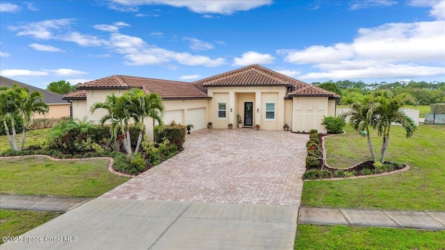 mediterranean / spanish home with driveway, stucco siding, a front lawn, a garage, and a tile roof