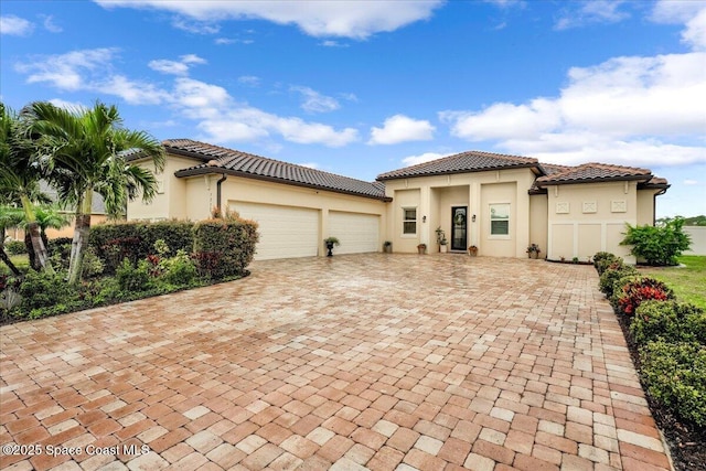 view of front facade featuring a tiled roof, stucco siding, an attached garage, and decorative driveway