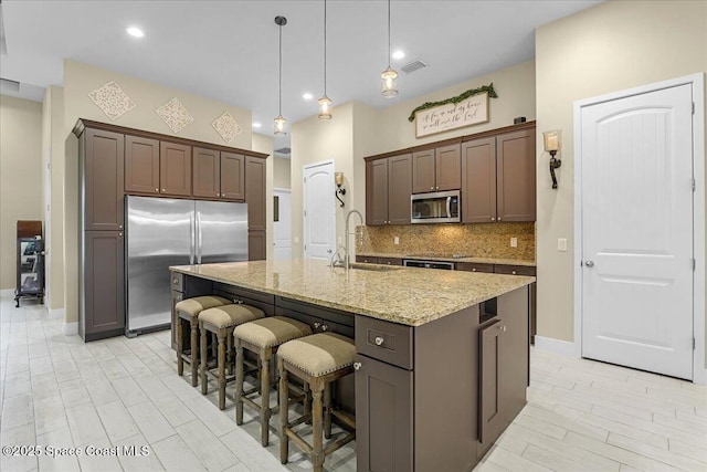 kitchen with light stone counters, visible vents, a sink, appliances with stainless steel finishes, and tasteful backsplash