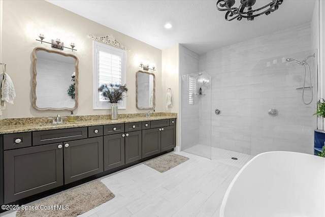 bathroom with a tile shower, double vanity, a freestanding bath, and a sink