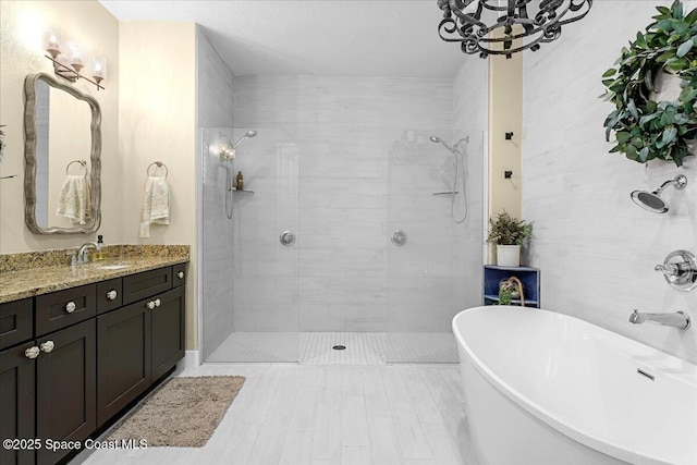 bathroom featuring a freestanding bath, vanity, a tile shower, and a chandelier