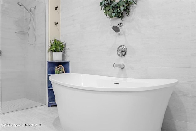 full bathroom featuring a soaking tub, tiled shower, and tile walls