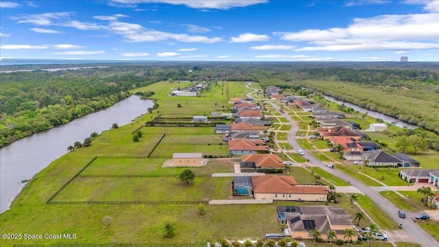 birds eye view of property featuring a forest view and a water view