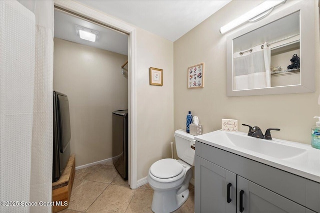 bathroom featuring toilet, washing machine and dryer, tile patterned flooring, baseboards, and vanity