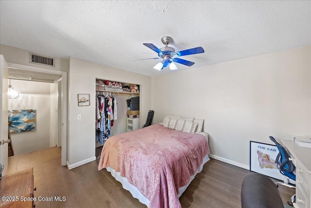 bedroom featuring a closet, visible vents, a textured ceiling, and wood finished floors