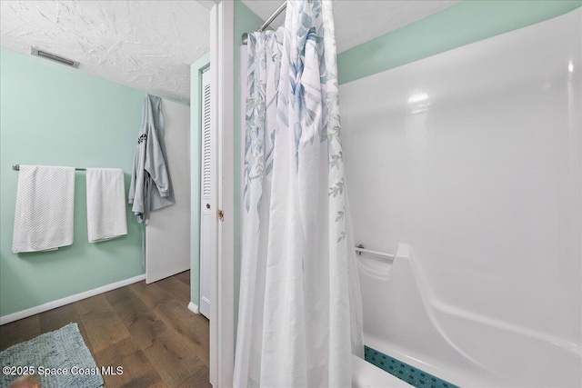 bathroom featuring visible vents, a textured ceiling, wood finished floors, a shower with shower curtain, and baseboards