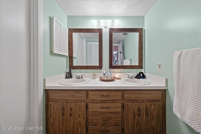 full bathroom with a sink, a textured ceiling, and double vanity