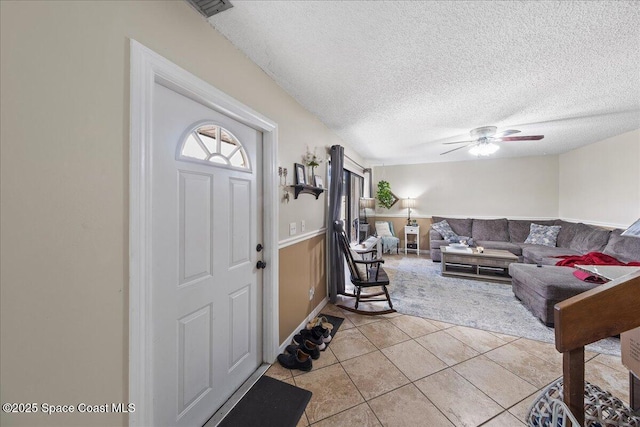 foyer entrance featuring light tile patterned floors, wainscoting, a textured ceiling, and ceiling fan