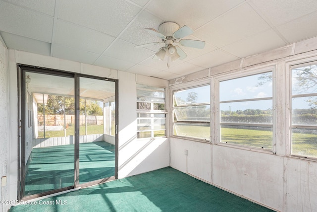 unfurnished sunroom featuring a wealth of natural light, a drop ceiling, and ceiling fan